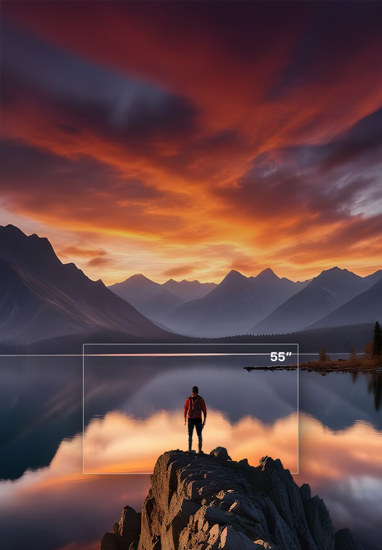 A man standing on a rock above a lake and mountains as the sun sets.