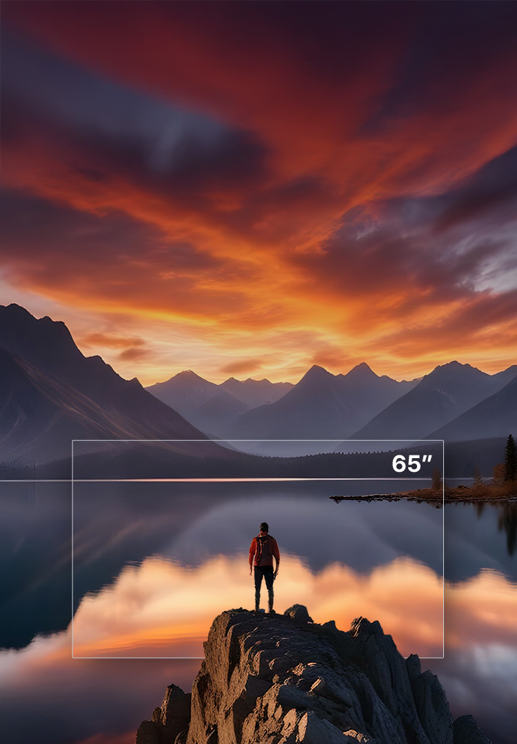 A man standing on a rock above a lake and mountains as the sun sets.