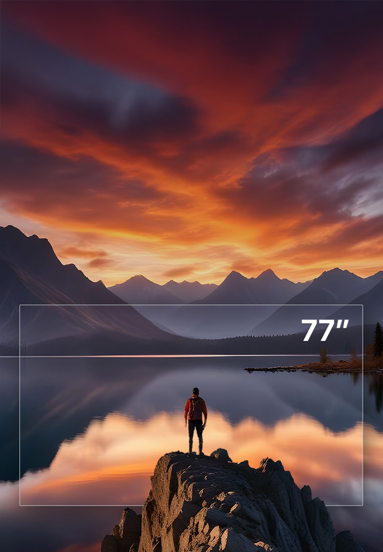 A man standing on a rock above a lake and mountains as the sun sets.