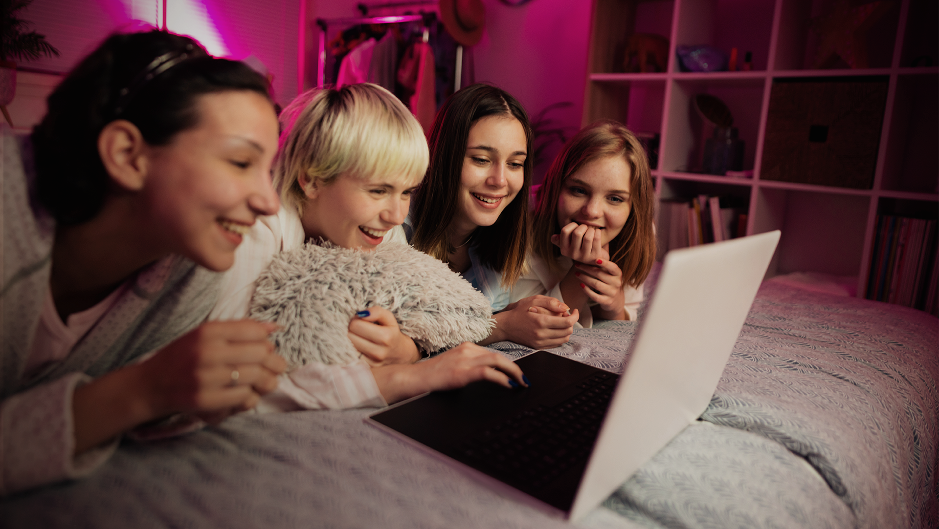 The image shows four female students watching a laptop together.