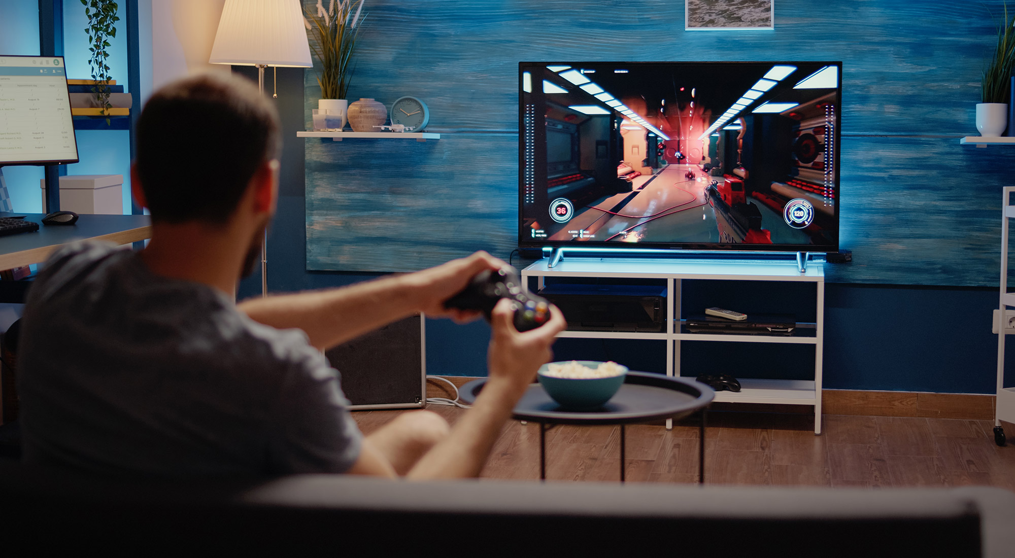 An image of a man playing an FPS game on a TV.